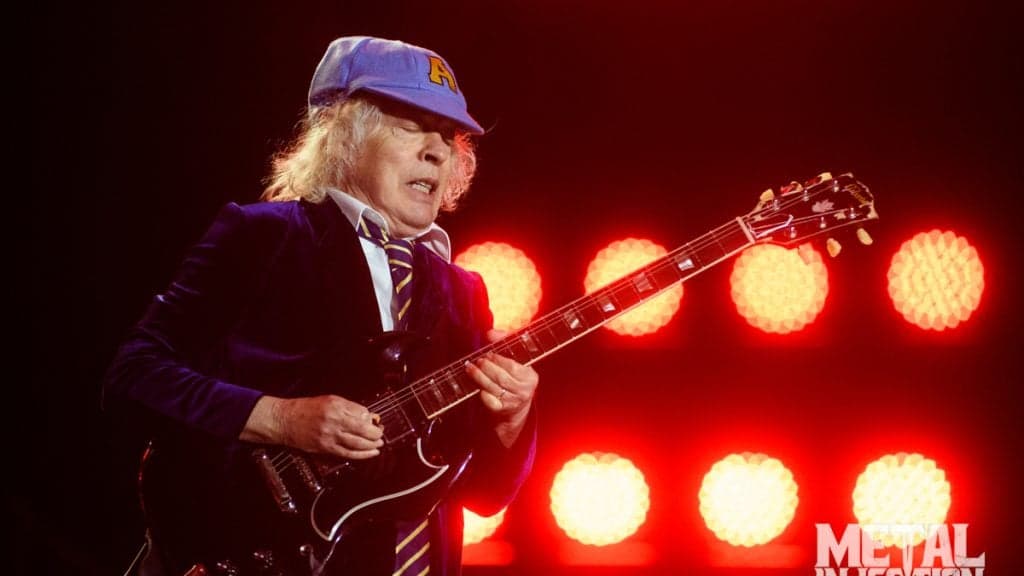 Angus Young signs a baby's autograph